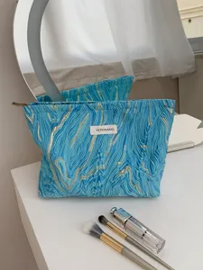 Detailed view of embossed blue makeup bag with gold wave pattern and storage capacity.