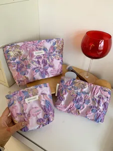 Detail shot of purple embossed floral cosmetic bag showing exquisite jacquard texture and craft.