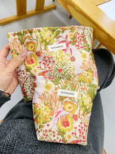 Detailed view of large capacity floral canvas cosmetic bag with zipper and custom woven brand label.