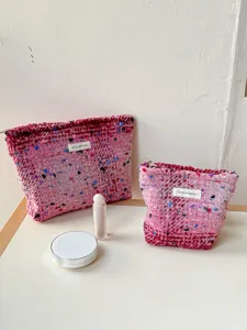 Detailed view of the pink tweed cosmetic bag, showcasing soft boucle fabric and neat zipper.