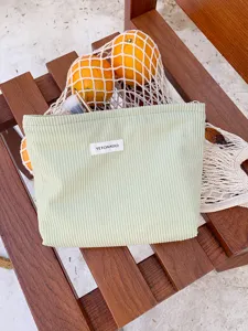 Close-up detail of light green corduroy makeup bag, soft fabric texture and neat stitching.