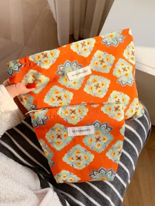 Detail of ethnic floral cosmetic bag, orange fabric with traditional pattern and zipper.