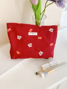 Close-up detail of the red cosmetic bag featuring cute gift box and mitten embroidery patterns.