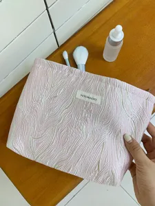 Pink embossed cosmetic bag detail shot, textured travel makeup pouch for daily storage.
