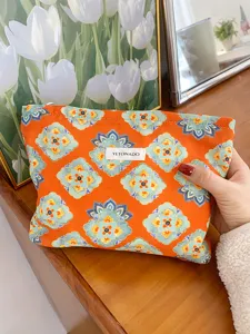 Detail view of ethnic floral cosmetic pouch, portable orange makeup storage bag close up.