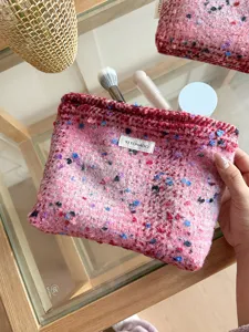 Close-up detail of the pink tweed cosmetic bag showing nice fabric texture and label.