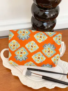 Ethnic style cosmetic bag detail, orange floral print pattern, portable travel makeup pouch.