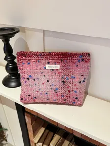Pink tweed cosmetic bag detailed view showing the soft woven textured fabric and brand label.