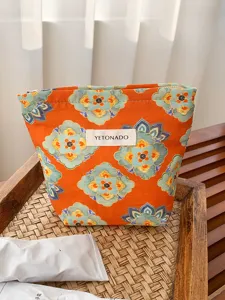 Detail shot of ethnic style large capacity makeup pouch in orange floral print with zipper design.