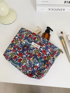 Detail view of the vintage floral cosmetic bag, showing fabric texture and zipper pocket.