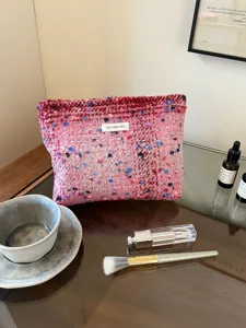 Pink tweed cosmetic makeup bag detail shot, showing textured woven fabric and zipper pouch.