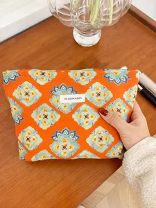 Ethnic style cosmetic storage bag detail, portable orange makeup pouch with traditional pattern.