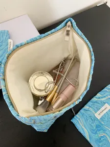 Detailed view of the blue embossed cosmetic bag showing interior capacity and makeup tools.