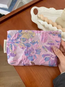 Purple embossed floral cosmetic pouch detail shot, portable travel makeup storage bag.