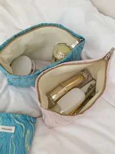 Detailed view of large capacity embossed cosmetic pouch open showing interior storage and lining.