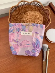 Close-up detail of purple floral cosmetic bag with textured jacquard fabric and storage props.