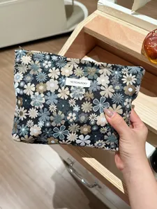 Close-up detail of a fabric cosmetic bag with floral jacquard pattern and woven label.