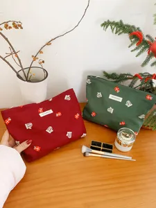 Detail shot of Christmas embroidered canvas makeup pouch with festive gift and mitten patterns.