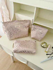 Detailed view of striped embossed cosmetic bags set on white vanity desk, portable travel storage.