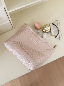 Detailed shot of pink and gold textured cosmetic makeup bag with beauty tools on clean table.