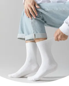 Gros plan sur les chaussettes montantes blanches côtelées respirantes portées par le modèle.