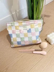 Pastel checkered makeup bag with zipper closure and front brand label, stylish cosmetic pouch.