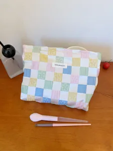 Quilted makeup pouch detail, colorful grid pattern with cute flower embroidery, soft bag.