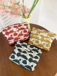 Close-up detail of canvas cosmetic storage bag with cute mushroom embroidery and zip closure.