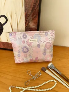 Close-up detail of a floral brocade cosmetic bag with label and makeup brush props.