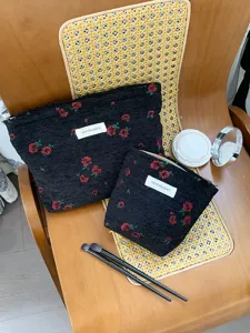 Detailed view of black woven cosmetic bags with red rose pattern, stylish daily clutch.