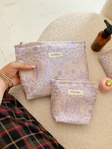 Detailed view of purple jacquard cosmetic bag with zipper and branded label in soft scene.