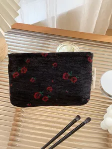 Detail view of the black floral cosmetic pouch with a side tag, stylish portable makeup bag close-up