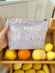 Detail view of the lavender floral cosmetic pouch featuring a woven brand label and zipper closure.