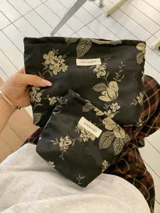 Detailaufnahme von schwarzen Blumen-Jacquard-Kosmetiktaschen mit Etikett, praktisches Design.