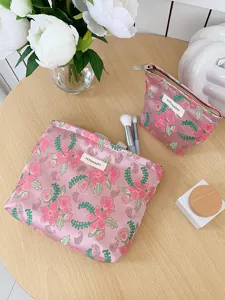 Close-up detail of pink floral fabric makeup bag with cute embroidery, portable cosmetic storage pouch.