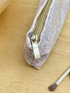 Close-up detail of the cosmetic bag zipper and floral fabric texture, elegant storage.