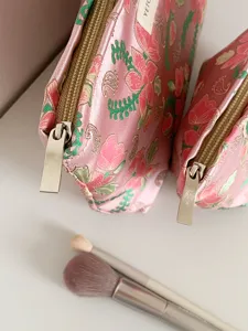 Detailed close-up of pink floral brocade cosmetic bag featuring a smooth metallic zipper.
