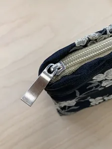 Detailansicht einer schwarz-weißen Kosmetiktasche mit Reißverschluss und Stoffstruktur.