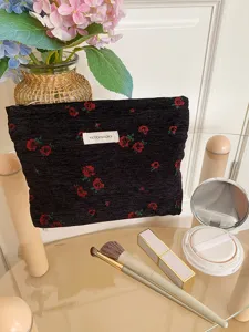Detail view of the black floral cosmetic bag showcasing textured woven fabric and zipper.