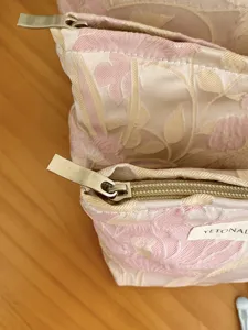 Gold thread floral jacquard cosmetic bag detail, elegant embossed texture pouch.