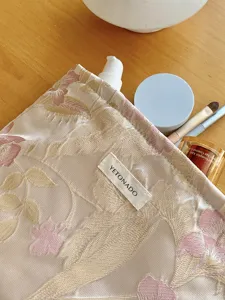 Gold silk floral jacquard cosmetic bag, pleated texture makeup pouch for skincare storage detail.