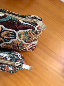 Detail shot of vintage woven cosmetic pouch with zip closure and retro floral pattern.