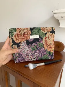 Vintage floral embroidered makeup pouch detail shot, showing exquisite tapestry texture and fabric.