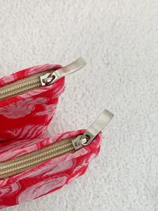 Detail shot of red patterned cosmetic pouch with durable metallic zipper for travel and daily use.