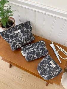 Detail shot of dark floral cosmetic bag set with soft canvas fabric and makeup brushes.