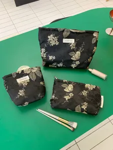 Detailansicht von schwarzen Kosmetiktaschen mit elegantem Blumen-Stickdesign.