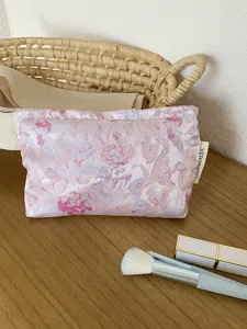 Close-up detail of the pink floral jacquard cosmetic pouch, showing vintage fabric texture.