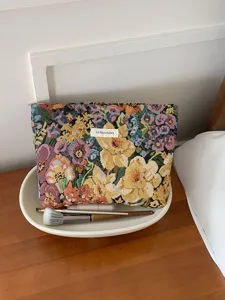 Close-up detail of the elegant floral embroidered jacquard makeup storage pouch placed on wooden desk.