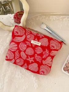 Close-up view of red shell jacquard cosmetic pouch detail displayed on white lace background.
