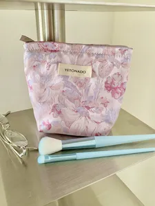 Detailed view of pink floral cosmetic makeup pouch, stylish small storage bag for travel daily.
